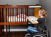 A paraplegic mom putting her baby down to sleep in a customized crib with a sliding door; Edmonton, Alberta, Canada