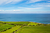 Grüne Felder an der irischen Küste mit dem Atlantik im Hintergrund an einem sonnigen Sommertag; Ballyvaughan, Grafschaft Clare, Irland