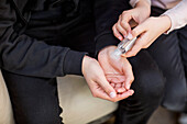 Weibliche Hände, die während der weltweiten Covid-19-Pandemie Handdesinfektionsmittel auf die Hände eines Mannes auftragen; Toronto, Ontario, Kanada