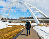 A man wearing a mask and gloves walks on a path outside using his smart phone during the Covid-19 world pandemic; Edmonton, Alberta, Canada