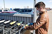 A young man gets a grocery cart during the Covid-19 World Pandemic; Edmonton, Alberta, Canada