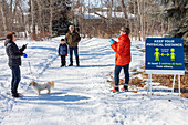 Familien stehen während der Covid-19-Weltpandemie auf einem Weg durch einen Park, um sich zu besuchen; St. Albert, Alberta, Kanada