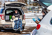 Two women sit in the back of their vehicles in a parking lot to visit during the Covid-19 world pandemic; St. Albert, Alberta, Canada