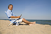 Mann sitzt am Strand und benutzt sein Mobiltelefon, Lake Michigan, USA