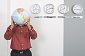 Geschäftsmann mit Weltkugel neben Uhren mit internationalen Zeitzonen stehend