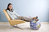 Geschäftsfrau mit den Füßen auf einem Globus sitzend