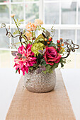 Floral centerpiece on table with burlap table runner