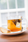 Tasse Tee in einem durchsichtigen Becher mit Zitronenbiskotti, Studioaufnahme