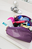 Damen-Toiletten- und Kosmetik-Reisetasche auf dem Badezimmertisch, gefüllt mit Zahnbürste, Lotion, Make-up und anderen Schönheitsprodukten, USA