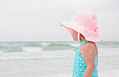 Porträt eines Mädchens im Kleinkindalter mit Sonnenhut am Strand und Blick auf den Ozean, Destin, Florida, USA