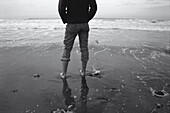 Back View of Man Standing in Surf on Beach