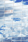 Sky and Clouds Reflected in Building Windows with For Lease Sign