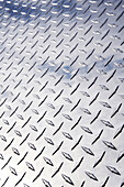 Low angle view of stainless steel diamond plate facade with reflection of clouds