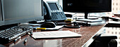 Schreibtisch im Büro mit Computermonitoren, Telefon und Papierkram, Kanada