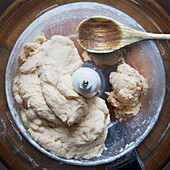 Close-up of uncooked pie dough in food processor with wooden spoon. studio shot