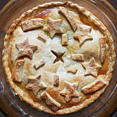 Overhead view of freshly baked apple pie with star shaped cut-outs on top, studio shot