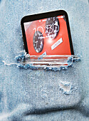 Close-up view of ripped pair of jeans with cell phone sticking out, Canada