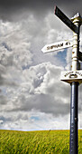 Old signpost with stormy sky and grassy field in the countryside in Sommerset, England