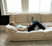 Teenage Girl Lying on Sofa Using Laptop Computer