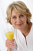 Reife Frau hält ein Glas Orangensaft