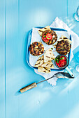 Gegrillte Burger und Pita-Brot auf Tablett mit Spatel auf blauem Holztisch im Studio