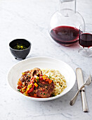 Risotto and Ossobucco (braised veal shank) on plate with red wine, studsio shot