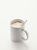 Soup and spoon in white mug, on white background, studio shot