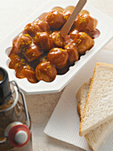Curry sausage in container with white bread, studio shot