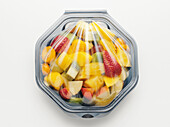 Fruit salad packaged in plastic container, on white background, studio shot