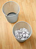 Overhead view of empty and used waste baskets on wooden floor, studio shot