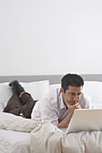 Man Using Laptop on Bed