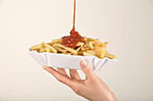 Woman Pouring Ketchup on French Fries