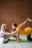 Yogalehrer mit Schüler, der die Tigerstellung einnimmt