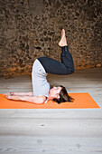 Frau im Yoga-Kurs macht Schulterstand