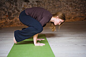 Frau im Yogakurs, die die Krähenstellung einnimmt
