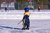 Kleiner Junge spielt Eishockey auf einem zugefrorenen Teich, Fuschlsee, Salzburger Land, Österreich
