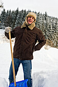 Mann leidet unter Rückenschmerzen beim Schneeschaufeln, Hof bei Salzburg, Salzburger Land, Österreich