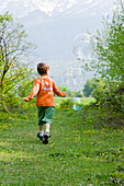 Junge rennend und Seifenblasen pustend, Salzburg, Österreich
