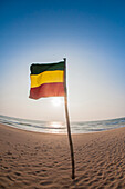 Deutsche Flagge auf Holzstab im Sand am Strand gegen den blauen Himmel, Indischer Ozean, Bentota, Galle District, Südprovinz, Sri Lanka