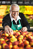 Verkäuferin beim Anordnen von Pfirsichen im Obst- und Gemüsegang