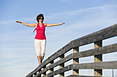Frau balanciert auf einem Holzgeländer, Honeymoon Island State Park, Florida, USA