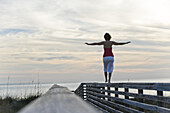 Frau balanciert auf hölzernem Geländer, Honeymoon Island State Park, Florida, USA