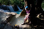 Frau sitzt an einem kleinen Wasserfall; Luang Prabang, Laos