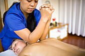 Masseuse Giving Back Massage With Elbows To Woman; Puerto Gallera, Mindoro Island, Philippines