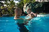Vater hält Baby im Schwimmbad; Dumaguete, Oriental Negros Island, Philippinen
