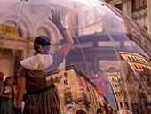 Frau im Inneren einer transparenten Glaskugel und eine Menschenmenge, die ihre Darbietung beobachtet; Rom, Italien