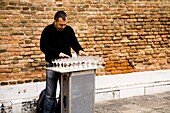 Straßenkünstler beim Arrangieren von Weingläsern; Venedig, Italien