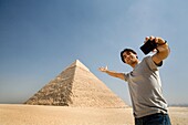 Mann, der ein Bild von sich selbst mit der Pyramide im Hintergrund macht