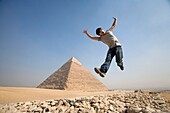 Mann springt in die Luft mit einer Pyramide im Hintergrund
