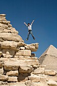 Mann springt auf einen Teil einer Pyramide in der Wüste